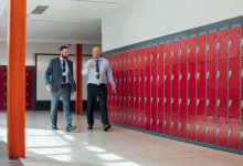 Two adults walking down a school hallway