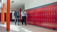 Two adults walking down a school hallway