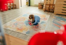 Young child playing while sitting on a rug
