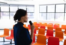 Woman practicing giving a speech to an empty room with orange seats