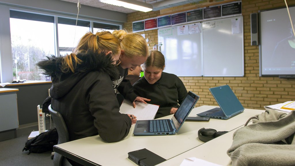 Three female students working together around a laptop with a project on screen