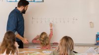 Photo of elementary student and teacher with numbers on whiteboard