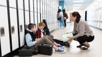 photo of teacher taking to middle school students in hallway