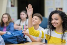 Photo of high school student raising hand in classroom