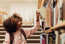 Photo of middle school student choosing book in library