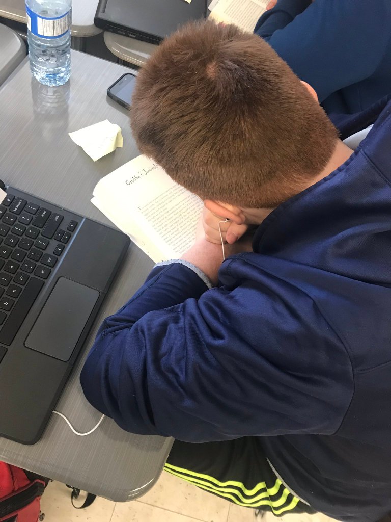 An image of a student listening to an audio book through headphones while he follows along in the print text.