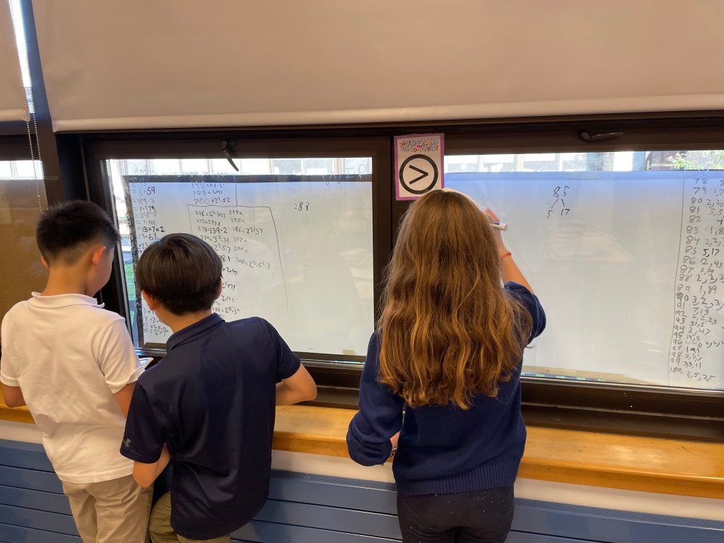 photo of elementary students writing math equations on white board