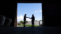 Photo of two men shaking hands in barn