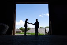 Photo of two men shaking hands in barn