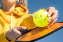 photo of person holding a pickleball ball and paddle