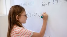 Photo of elementary student doing math problem on whiteboard