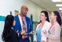Principal talking to teachers in school hallway