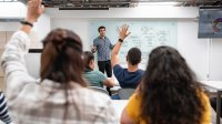 Students raising their hands while a teacher leads discussion