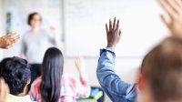 Photo of students raising hands in high school classroom