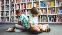 Photo of two elementary age boys reading books