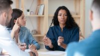 Woman talking to coworkers, representing a school leader with a divided staff