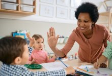 photo of pre-kschool teacher high fiving student