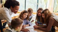 Photo of elementary school teacher working closely with students