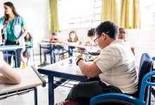 Student in wheelchair working at his desk in class, representing the idea of disability inclusion in school