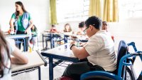 Student in wheelchair working at his desk in class, representing the idea of disability inclusion in school