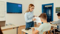 Teacher handing paper to student