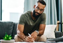 Photo of man writing in journal at home, representing the idea of teacher reflection