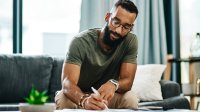 Photo of man writing in journal at home, representing the idea of teacher reflection