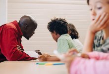 Photo of elementary teacher working closely with two students