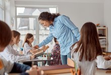 Photo of middle school teacher talking to student in classroom