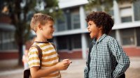 Two elementary students talking outside of school