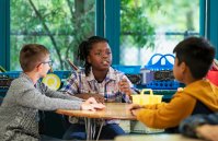 Three multiracial elementary school boys talking to each other in classroom