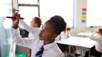 Photo of middle school students writing on white board in classroom