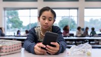 Photo of middle school student using cellphone at lunch