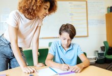 elementary school teacher assisting student with sentence stem writing