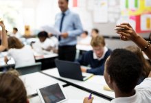 Photo of middle school classroom with student raising hand