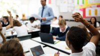 Photo of middle school classroom with student raising hand