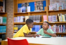 Two young male students working together in a library
