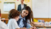 Photo of teacher watchng new teacher work with elementary student