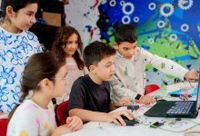 Elementary students focusing on critical thinking and creativity as they work together on a project with a laptop