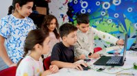 Elementary students focusing on critical thinking and creativity as they work together on a project with a laptop