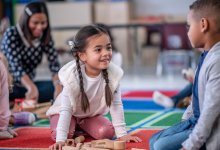 Photo of pre-students playing independently with teacher in background