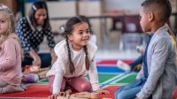 Photo of pre-students playing independently with teacher in background