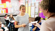 Photo of student turning in work to teacher