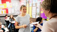 Photo of student turning in work to teacher