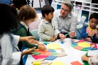 A small group of elementary students working with blocks as a teacher guides them