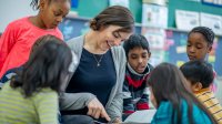 Students in english language arts class surrounding a teacher reading a picture book