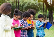 A group of elementary students standing outside writing in notebooks to celebrate the spring equinox