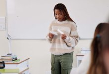 Student looking at notecards during class presentation, representing student anxiety about public speaking