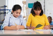 Two ell students observing leaves and taking notes