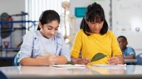 Two ell students observing leaves and taking notes